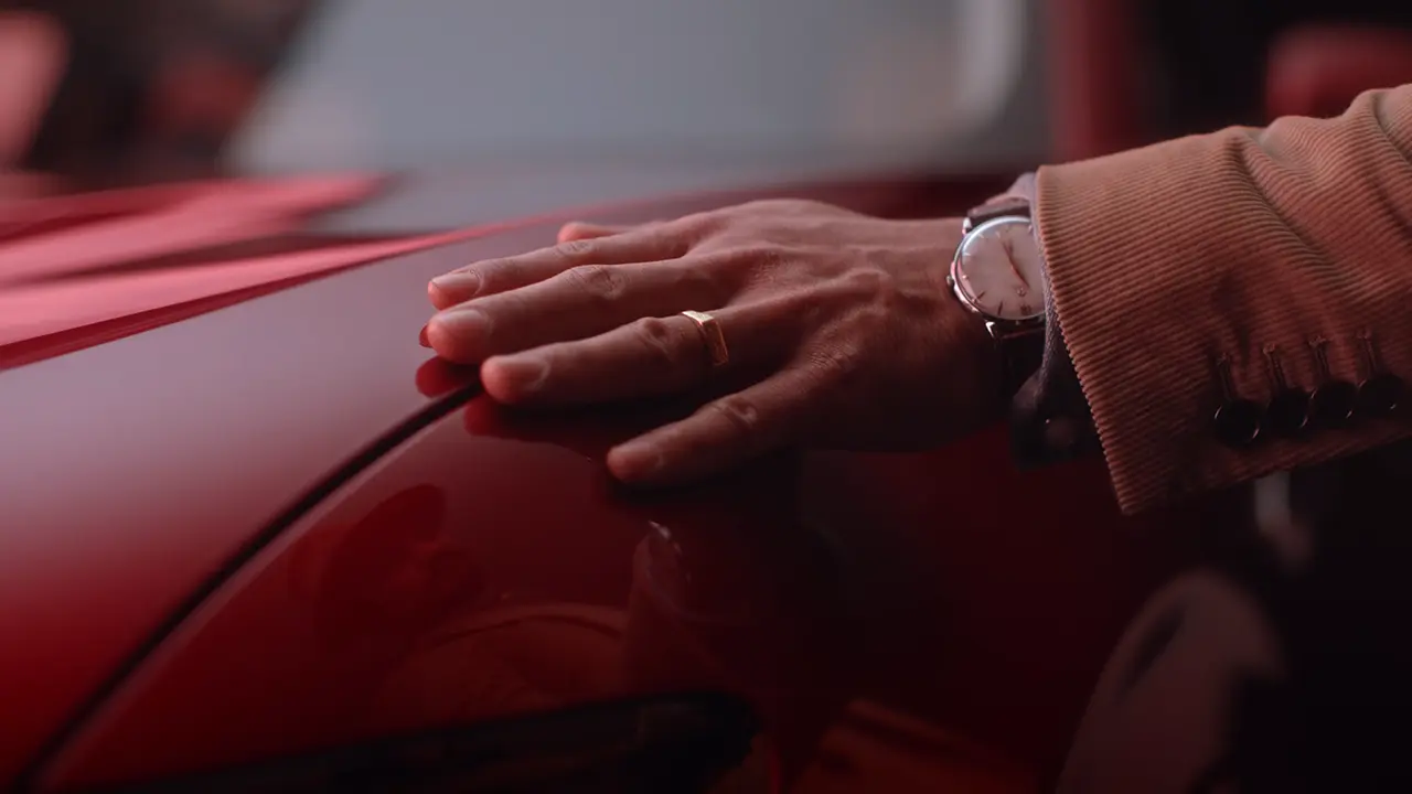 Cornland Studio - Gros plan d'une main qui caresse une voiture rouge.