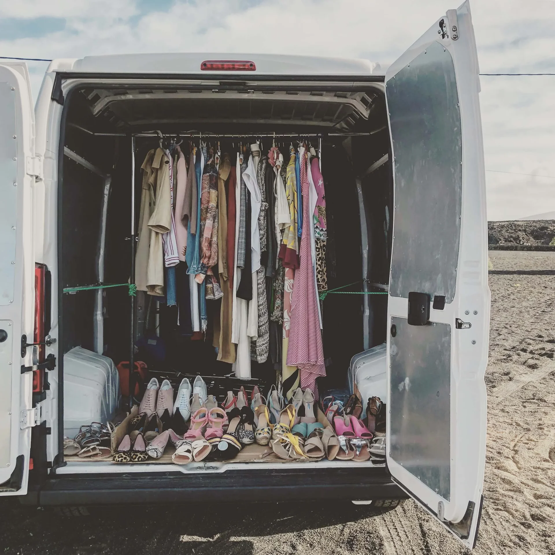 Cornland Studio - Le coffre d'une camionette ouvert avec à l'intérieur une pendrie remlie d'habits colorés.